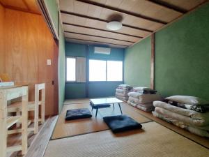 Pokój z zielonymi ścianami, stołem i poduszkami w obiekcie Amino Guesthouse Bench w mieście Kyotango