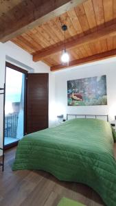 a bedroom with a green bed with a wooden ceiling at Al Castello in Morano Calabro