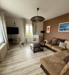 a living room with a couch and a tv at La Maison des phares in Lion-sur-Mer