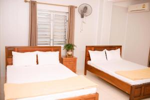 two beds in a room with white walls at Thảo Nguyên Hotel in Vinh