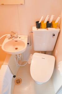 La salle de bains est pourvue de toilettes blanches et d'un lavabo. dans l'établissement Tutulu502, à Osaka