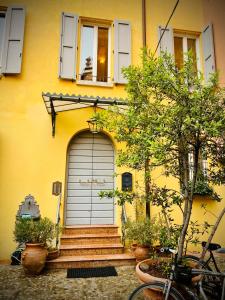 a yellow house with a garage door and a tree at PINK HOUSE TORTELLINOSUITE Modena in Modena