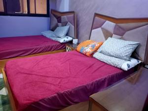 two beds in a room with purple sheets at شقة فندقية في بورسعيد in Port Said