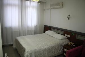 a bedroom with a bed with white sheets and a window at Yeni Kosk Esra Hotel in Konya