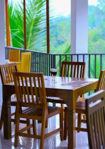 una mesa de madera con sillas y una copa de vino en Ella Sriya Holiday Resort, en Ella