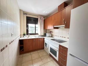 una cocina con armarios de madera y un aparato blanco en Coto de Sancti Petri, en Chiclana de la Frontera