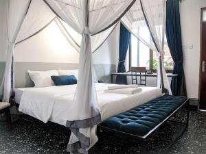 a bedroom with a canopy bed with a blue bench at Explorers Hub in Kampala