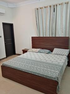 a bedroom with a large bed with a wooden headboard at 3-Beds with Terrace & Amenities in Karachi