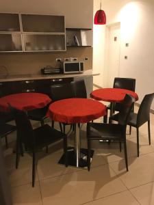 uma cozinha com quatro mesas e cadeiras vermelhas em MagloInnFiera em Bolonha