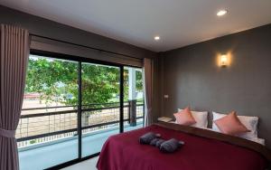 a bedroom with a large bed with a large window at Kodtalay Resort in Chao Lao Beach