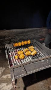 a grill with food cooking on top of it at MudHouse Retreat, Sarajara in Bīr