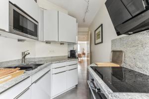 a kitchen with white cabinets and a sink at Charme et authenticité à Montmartre by Weekome in Paris