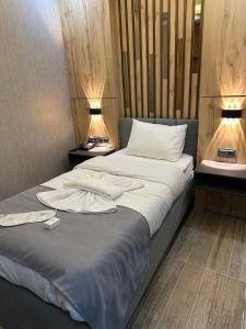 a bedroom with a bed with white sheets and two lamps at world say hotel in Bostaniçi
