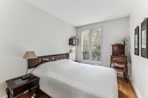 a white bedroom with a bed and a window at Charme et authenticité à Montmartre by Weekome in Paris