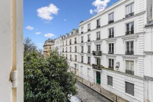 a row of white buildings on a street at Charme et authenticité à Montmartre by Weekome in Paris