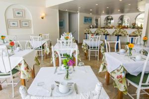 a restaurant with white tables and chairs with flowers on them at Hotel Doce Mar in Búzios