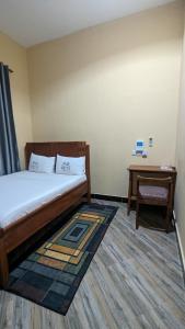1 dormitorio con cama, escritorio y mesa en Rest Inn Lounge & Lodge, en Dar es Salaam