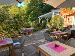 een patio met houten tafels en stoelen en roze servetten bij Hotel Altes Dichterhaus in Timmel