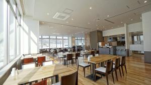 una sala da pranzo con tavoli e sedie in legno di Hotel La'gent Plaza Hakodate Hokuto a Hokuto