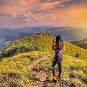 una mujer de pie en una colina tomando una foto en Abimansala Resort, en Hunnasgiriya
