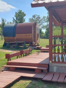 eine Holzterrasse mit Bänken und einem Pavillon in der Unterkunft MANÓ HORDÓHÁZAK in Pázmánd