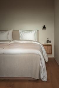 a large white bed with white sheets and pillows at Hotel Vyn in Simrishamn