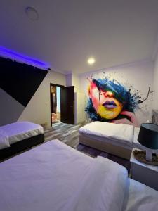 a bedroom with two beds with a painting on the wall at Bora Bora in Durat  Alarous