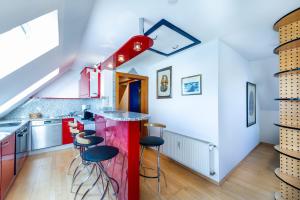 a kitchen with a red counter and stools at Apartmenthaus Pastner am Teich in Übelbach