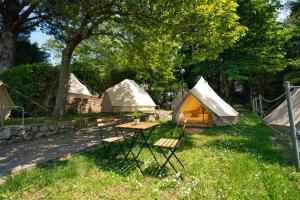 a group of tents and a table and chairs in the grass at Kampaoh Playa Troenzo in Celorio