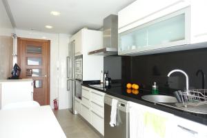 a kitchen with white cabinets and a black counter top at Palau de Congressos Great Stay Room in Valencia