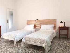 twee bedden in een witte kamer met een tafel bij appartamenti olivo in Vigevano
