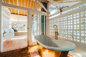 a bathroom with a tub in a room with windows at Mandala The Bay in Nusa Lembongan