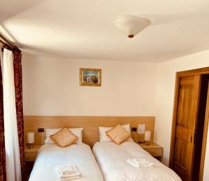 una camera con due letti con lenzuola bianche di Affittacamere Buenavista a Champoluc