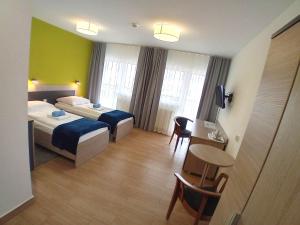 a hotel room with two beds and a table at Ośrodek Wypoczynkowo-Leczniczy OPOLE w Dźwirzynie in Dźwirzyno