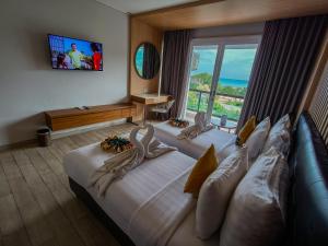 a hotel room with two beds and a large window at Raja Hotel Kuta Mandalika Resort & Convention in Kuta Lombok