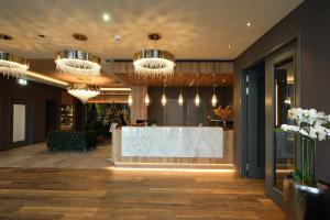 a lobby with a reception desk and chandeliers at Hotel Demas München-Unterhaching in Unterhaching