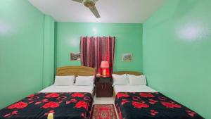 two beds in a small room with green walls at Hotel Padma Residential Jatrabari in Dhaka