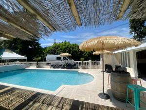 Spay的住宿－Le Domaine des 24 Heures Piscine 8pers，一个带草伞和椅子的游泳池