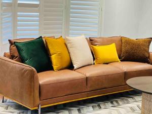 un divano marrone con cuscini di colore diverso di Maroubra Gem Close to Everything Sleep 16 a Sydney