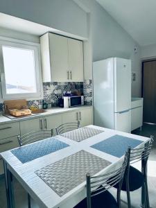 a kitchen with a table and a white refrigerator at Aris Apartment in Nea Peramos