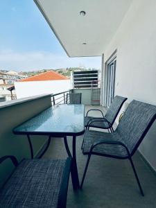 a balcony with two chairs and a glass table at Aris Apartment in Nea Peramos