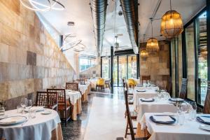 un restaurante con mesas y sillas blancas y ventanas en Hotel Boutique Mas Passamaner, en La Selva del Camp