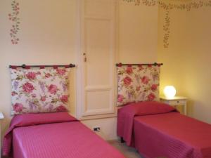 dwa łóżka w pokoju z różowymi prześcieradłami w obiekcie Mimì Apartment w Lukce