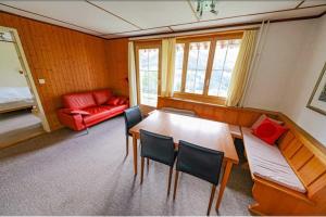 a room with a table and chairs and a red couch at Chalet Alpenmoos (150m2 - max.11) in Lenk