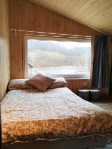 Bett in einem Zimmer mit einem großen Fenster in der Unterkunft Agroturystyka 3 chaty red black I nanna in Młynary