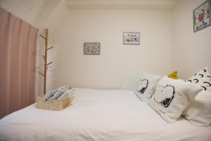 una camera da letto con un letto con lenzuola e cuscini bianchi di Tookin house 池袋 a Tokyo Altre 32 foto