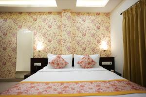 um quarto com uma cama grande e papel de parede floral em Voyage Comfort Primer Inn em Siliguri
