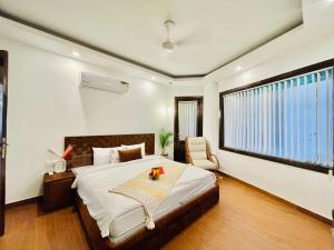 ein Schlafzimmer mit einem Bett, einem Stuhl und einem Fenster in der Unterkunft BedChambers Serviced Apartments South Extension in Neu-Delhi