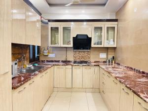 uma grande cozinha com armários de madeira e bancadas de mármore em BedChambers Serviced Apartments South Extension em Nova Deli
