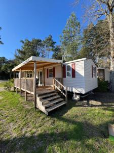 a tiny house with a porch and a deck at mobilhome grand confort 6 couchages Cap Ferret in Lège-Cap-Ferret